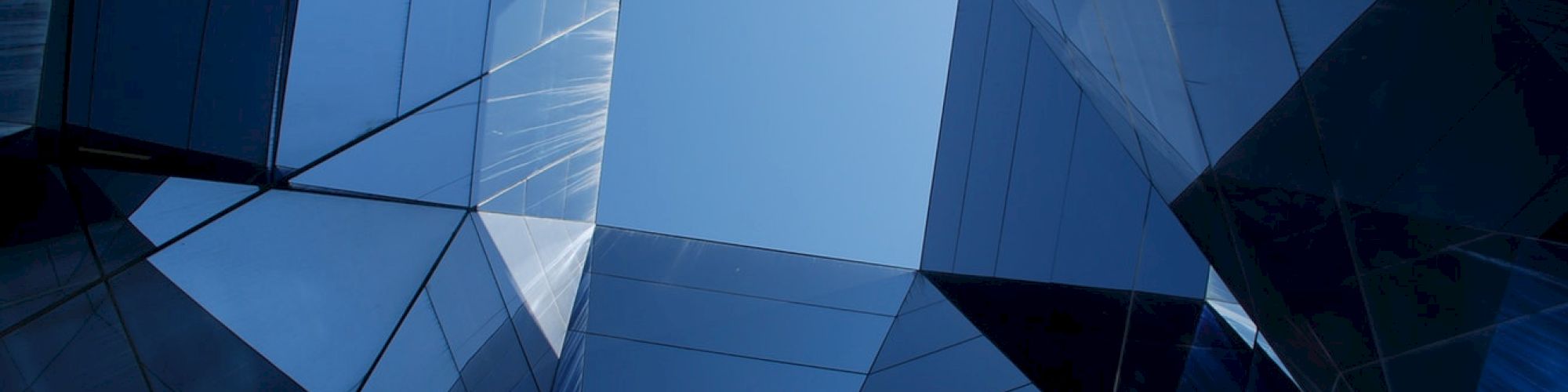 The image shows the sky framed by the geometric patterns of modern architectural glass and steel structures, creating a visually striking composition.