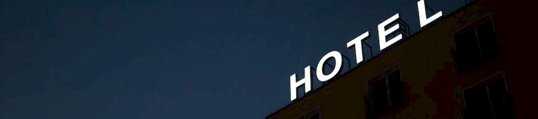 The image shows the top portion of a building against a dark sky with the word "HOTEL" in illuminated letters.