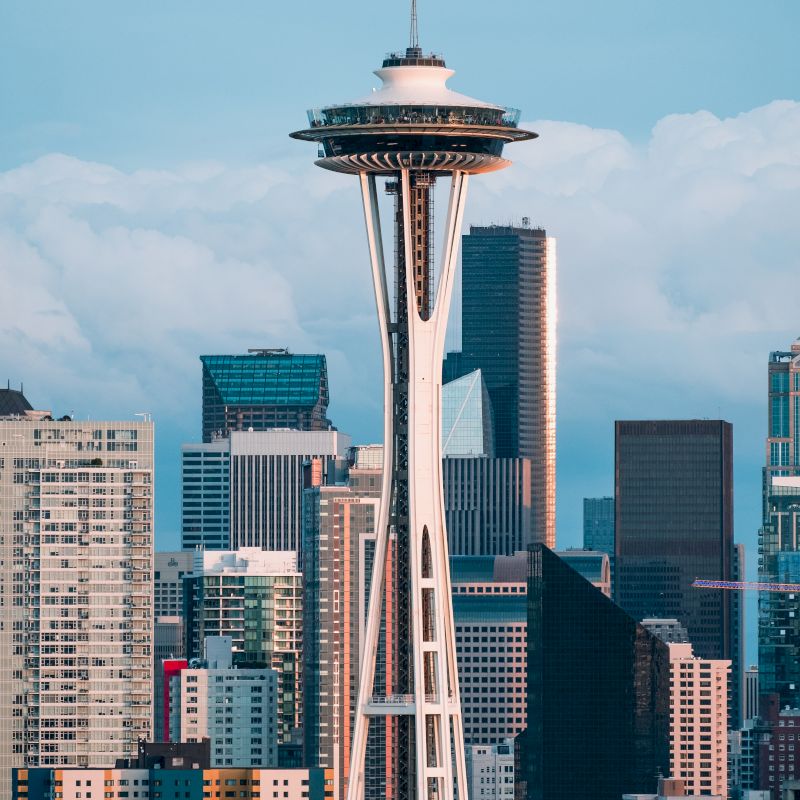 The image features the Space Needle, a famous landmark, against a backdrop of the Seattle skyline with various buildings and skyscrapers.