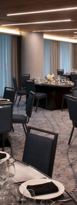The image shows an elegantly set banquet hall with round tables, each adorned with place settings, flowers, and candles.